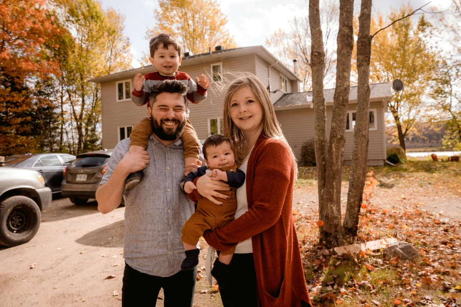 A happy family of 4 standing in front of their house