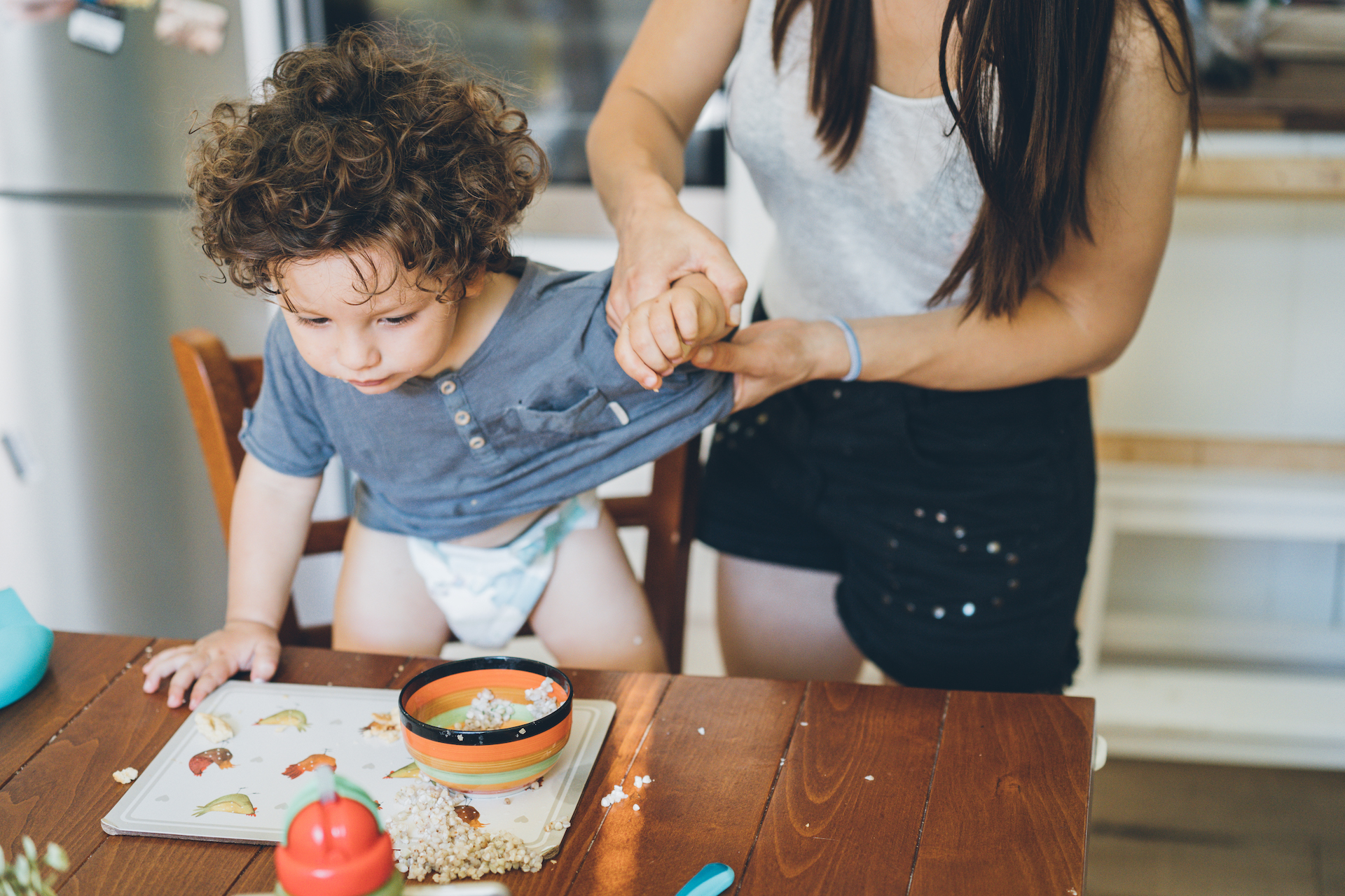 Mother undressed the t-shirt to her baby boy after lunch