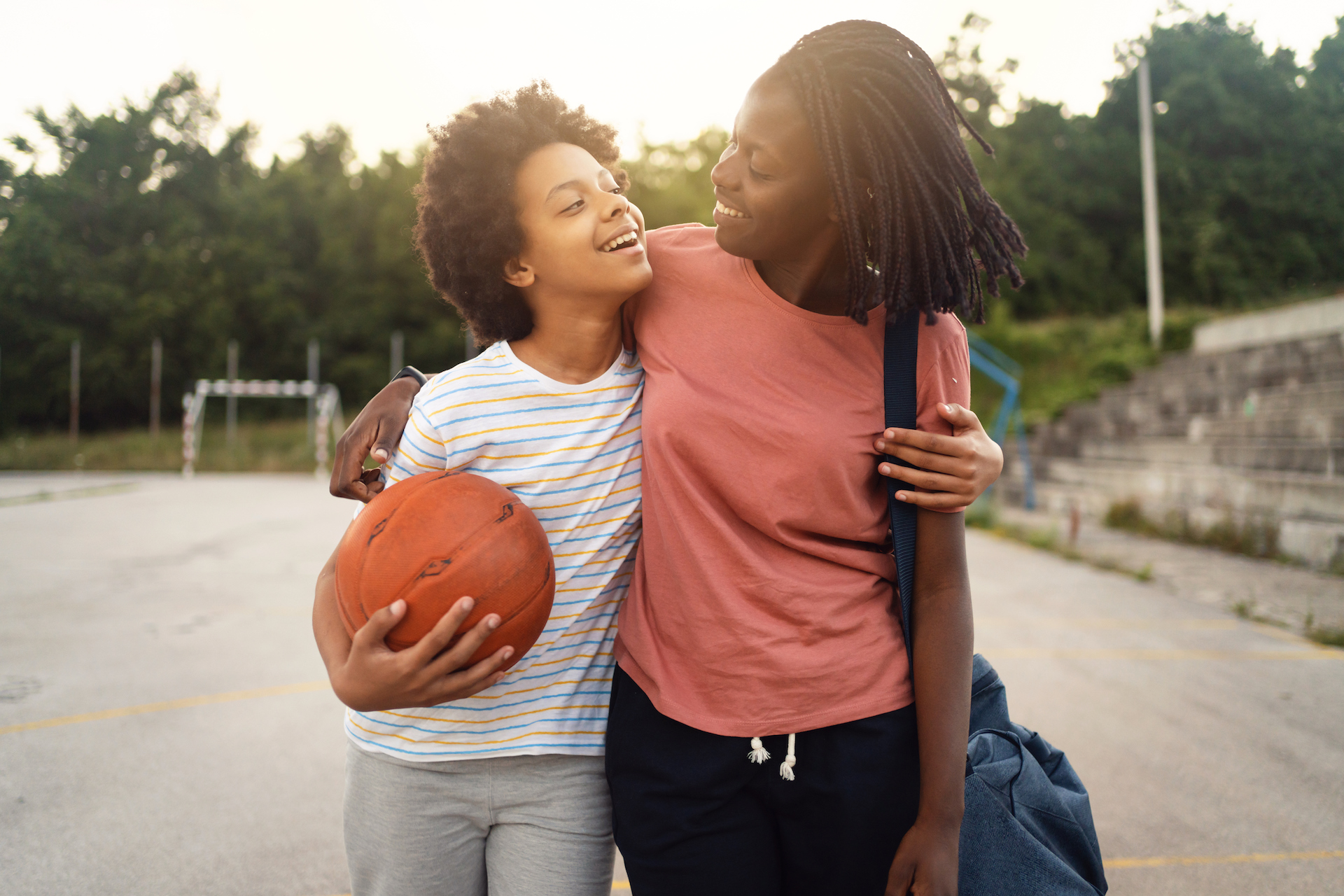 Cheerful and proud mother of Black ethnicity, picking up her teen daughter from her basketball practice